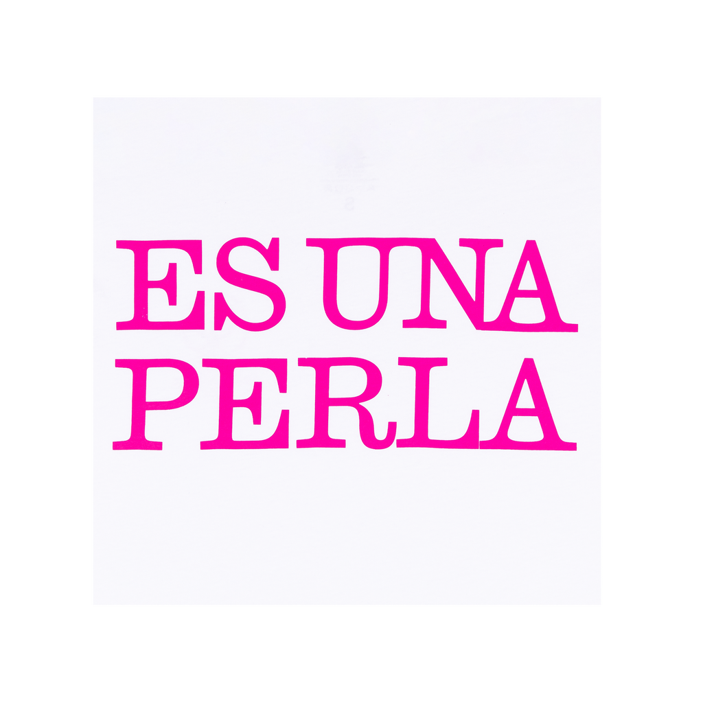 Close-up view of a white T-shirt with bright pink text on the back reading “ES UNA PERLA” in uppercase letters.